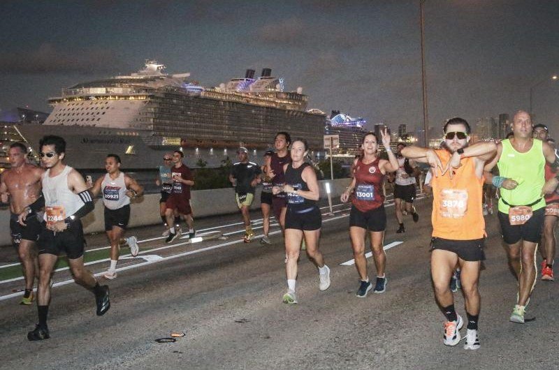 Runners on a Miami causeway at night with a cruise ship behind them